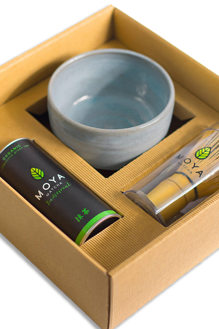 Gift set with a ceramic bowl, can, bamboo whisk, and tube of matcha green tea labeled 'Moya' on a white background - Pangolins