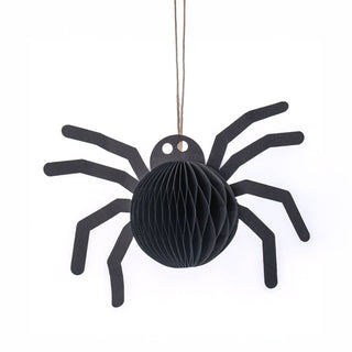 A black spider-shaped hanging decoration made of honeycomb paper, suspended by a thin string against a plain white background.