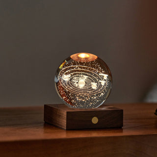 Crystal ball with solar system model on a wooden base against a dark background - Pangolins