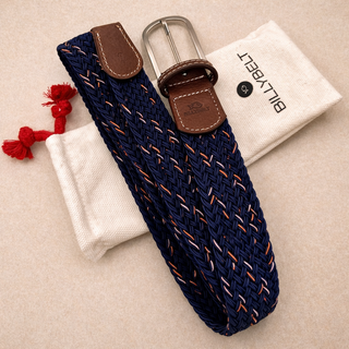 Navy woven belt with brown leather buckle on a beige surface, accompanied by a white pouch and red tassels.