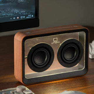 Wooden speaker with brand logo on a desk next to a computer monitor - Pangolins