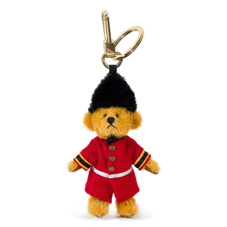 Plush Merrythought mini bear keychain in a red Guardsman uniform with a black hat on a white background