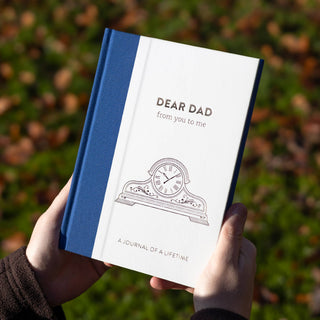 Book titled 'Dear Dad from you to me' held by a person with a blurred natural background - Pangolins