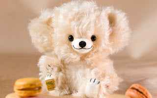 Merrythought Limited Edition Collectable Cheeky Bear, vanilla coloured bear sitting with macarons - Pangolins