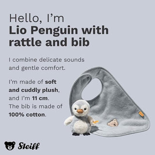 A light gray plush baby bib with a matching penguin toy, shown on a pale gray background with descriptive text. The bib has a small embroidered bear face and a small orange tag.